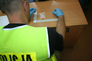 policjant przeprowadza oględziny zabezpieczonym tabletek