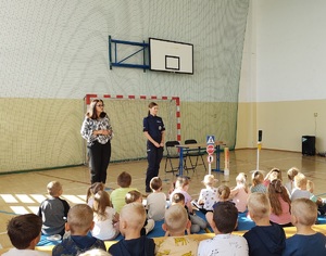 policjantka stoi przed dziecmi na sali gimnastycznej