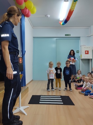 policjantka uczy dzieci jak przechodzić przez pasy