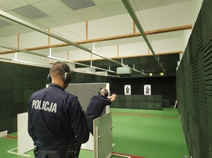 jeden policjant zza zaslony kieruje broń do celu