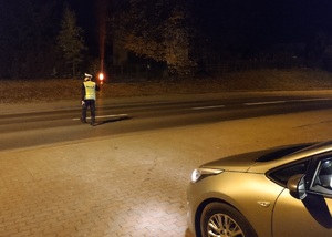 policjant na drodze zatrzymuje pojazd czerwona latarką