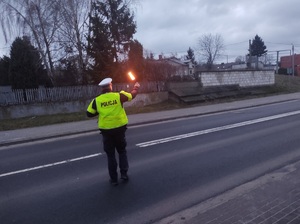 policjant na drodze daje znak latarka do zatrzymania